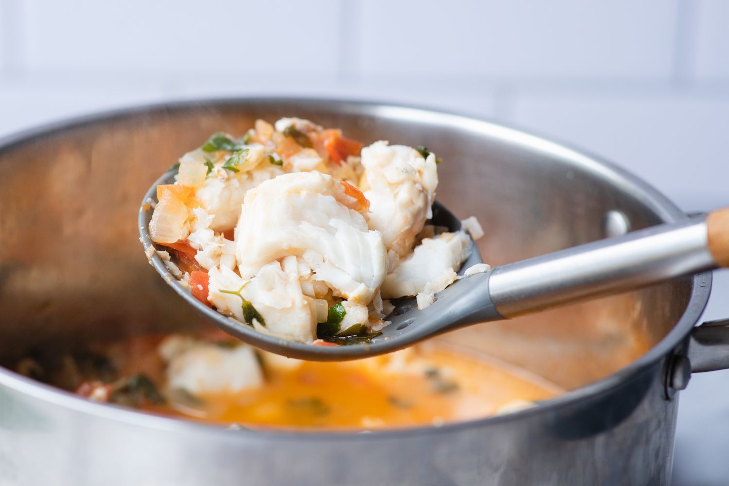 Ladling fish soup out of a pot.