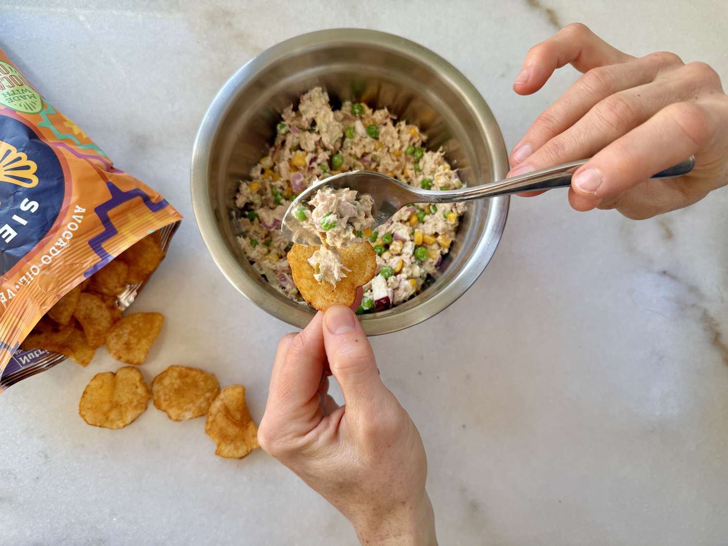 Matthew McConaughey's Tuna Salad in a bowl, hands spooning a bit onto a potato chip