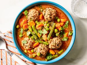 A bowl of albondigas soup with meatballs and vegetables