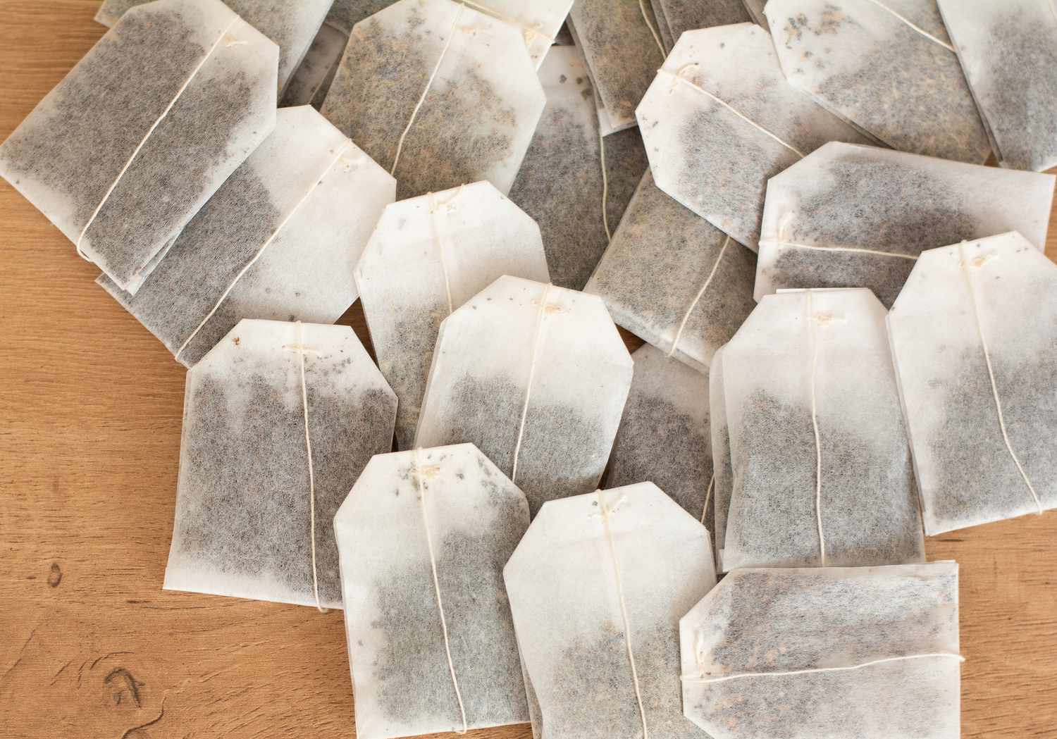 Top view of a lot of tea bags in a pile on a wooden background.