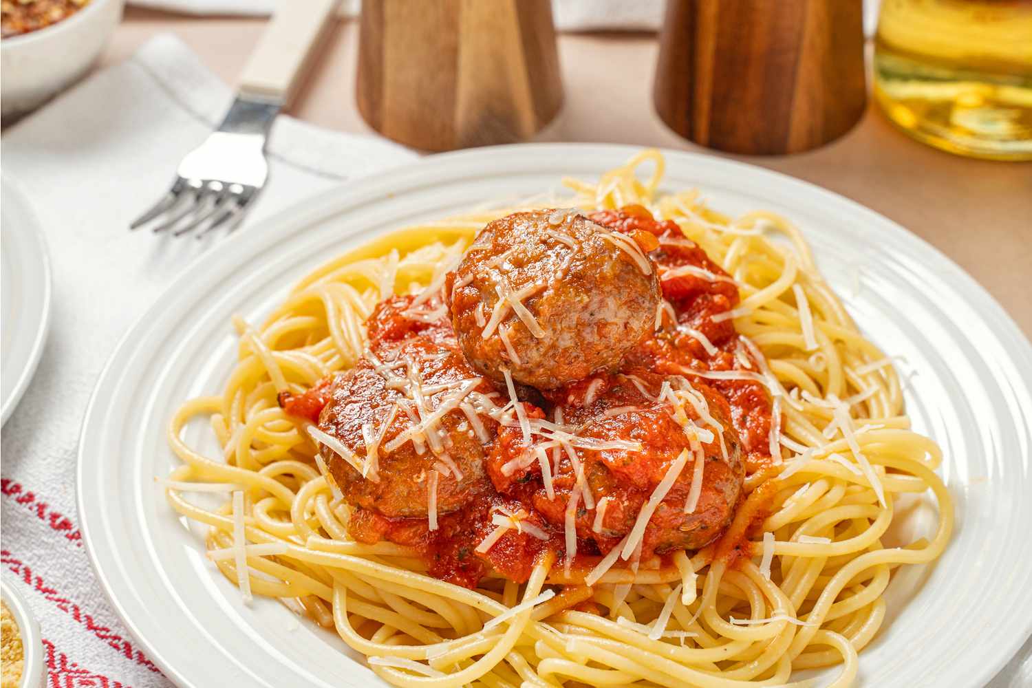 Plate of spaghetti with meatballs and tomato sauce topped with grated cheese