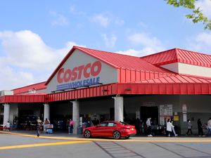 Entrance of a Costco Wholesale store showing people and a car in the front area