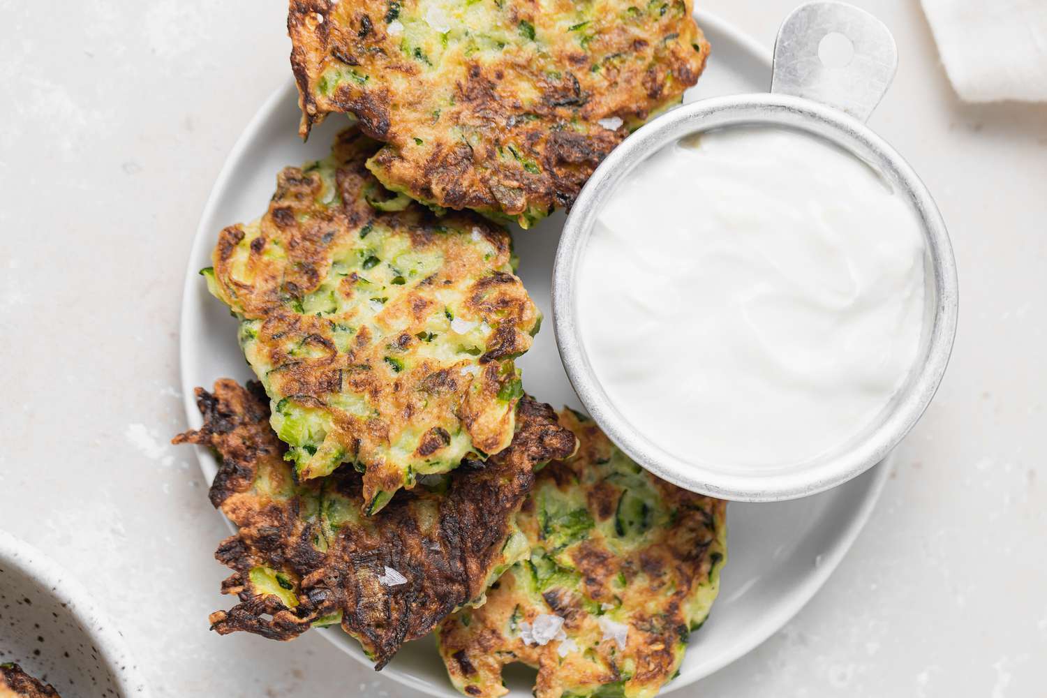 Overhead view of zucchini fritters served with a dipping sauce.