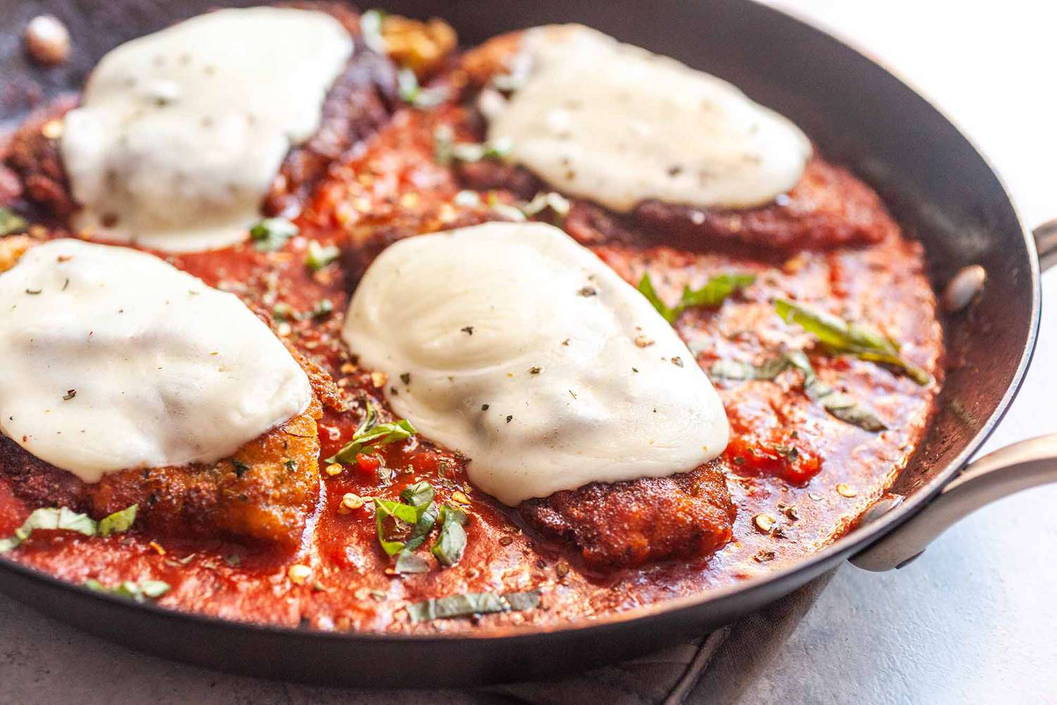 A skillet with chicken parm ready to serve