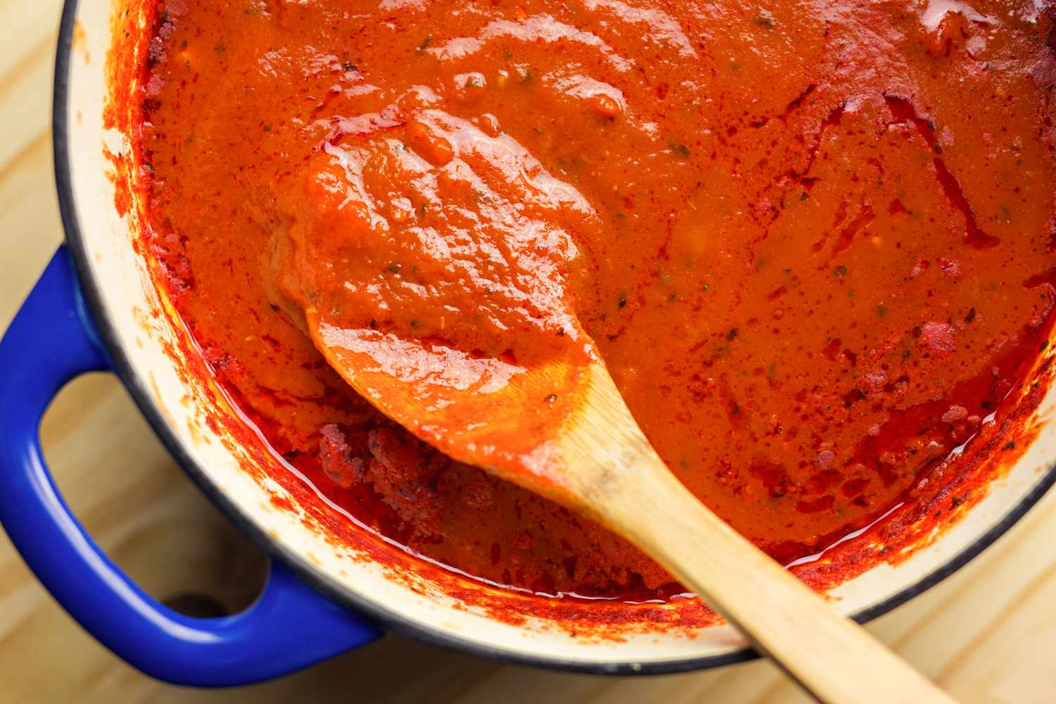 Tomato sauce in a pot and mixed with a wooden spoon