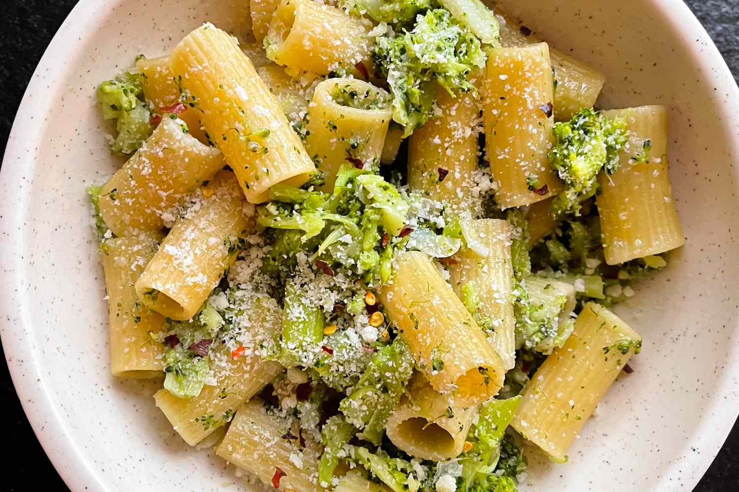 Closeup overhead shot of a bowl of rigatoni pasta with broccoli and parmesan cheese