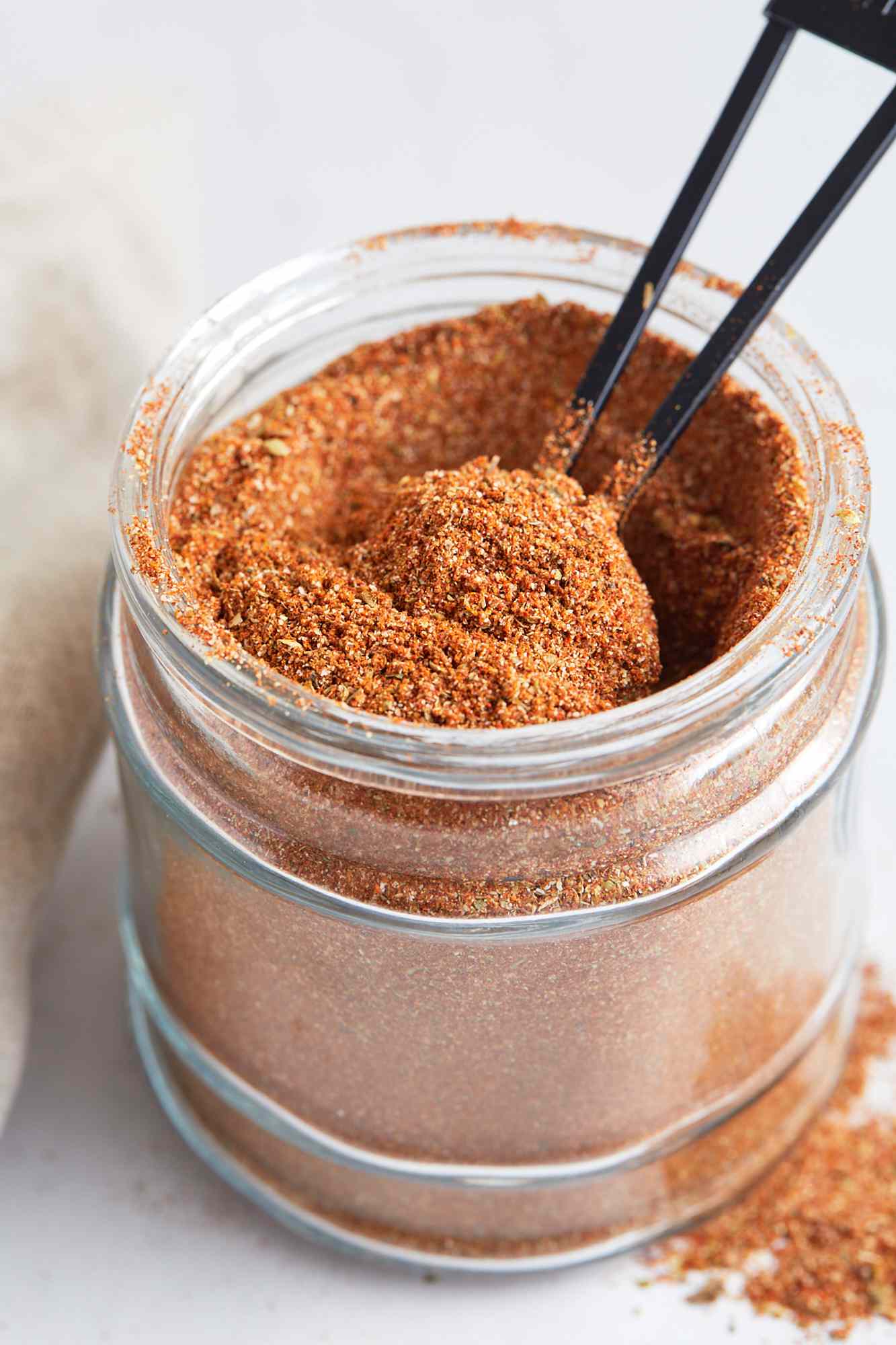 A jar of Cajun seasoning with a spoon in it