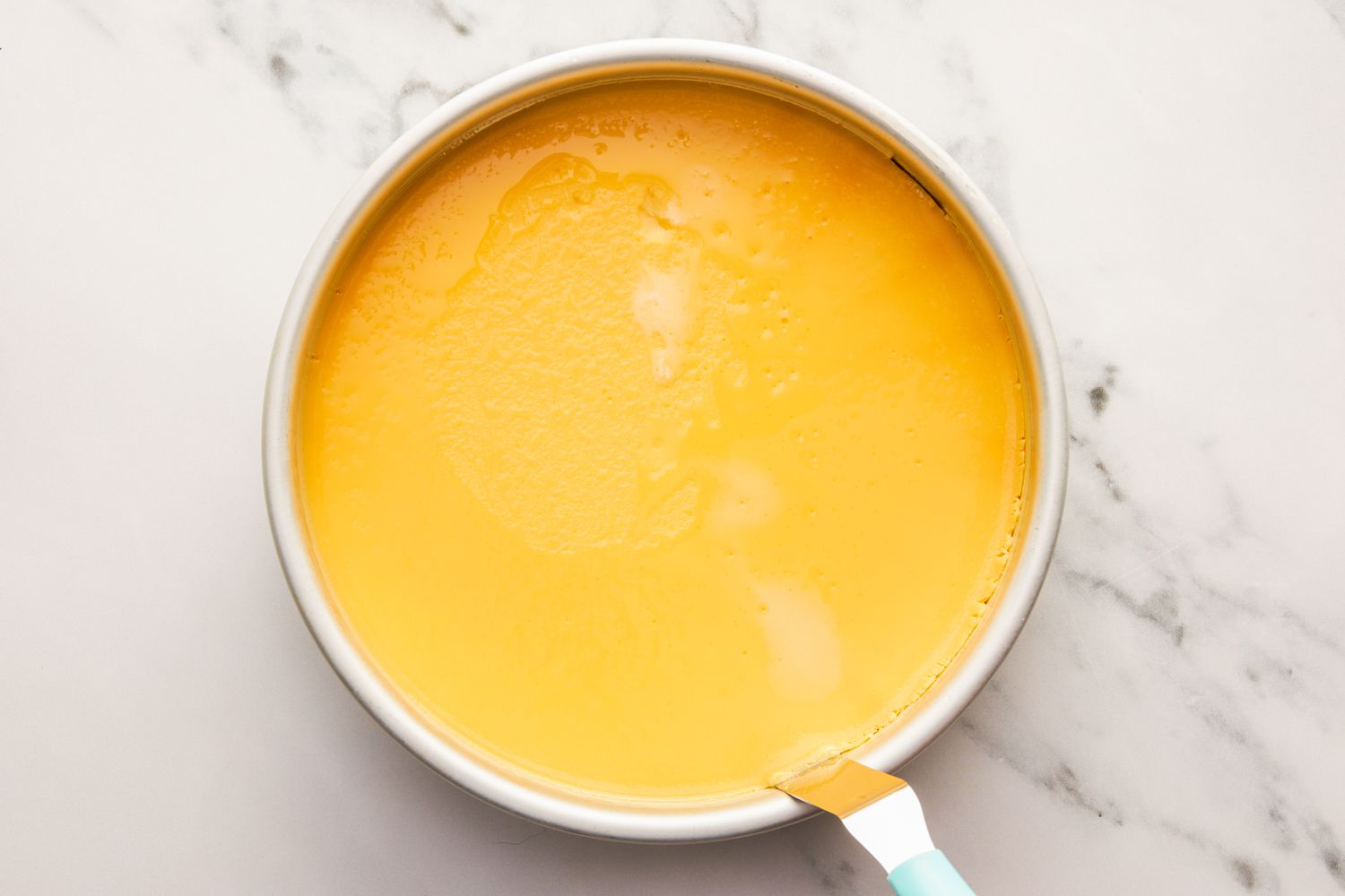 Baked flan in a round cake pan, running a palette knife around the edge for flan recipe