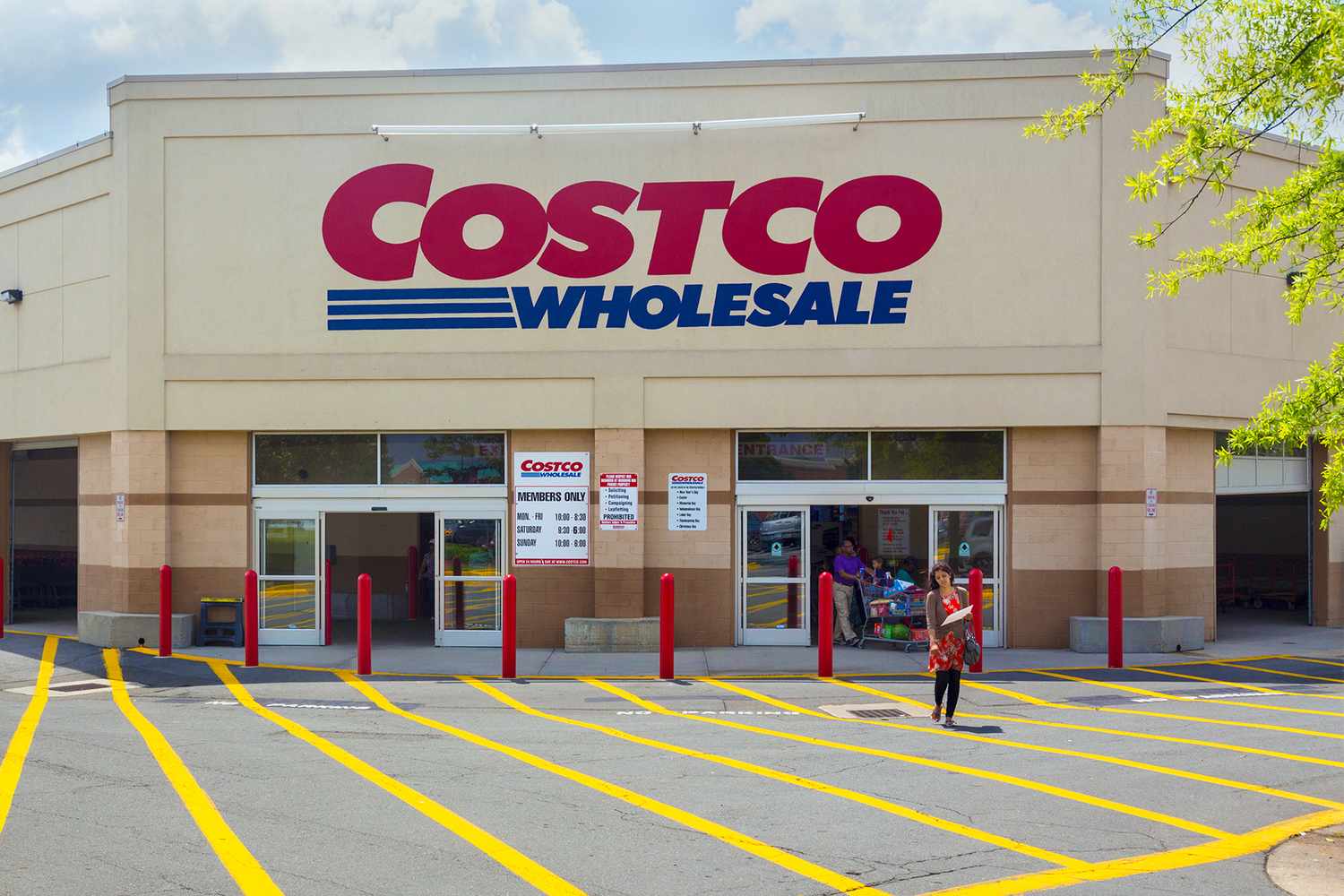 Exterior view of a Costco Wholesale store with a person walking in the parking lot