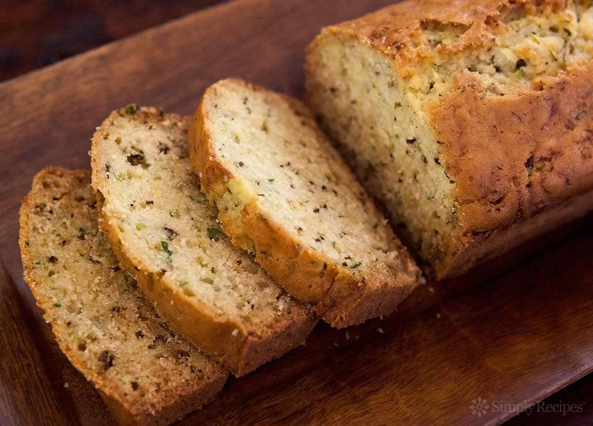 A cutting board with a loaf of zucchini bread, sliced and ready to serve