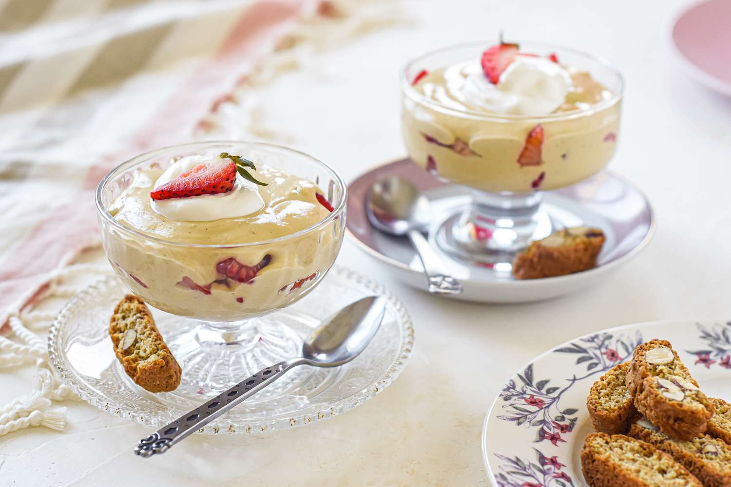 Two parfait glasses with sabayon sauce topped with cream and a strawberry.