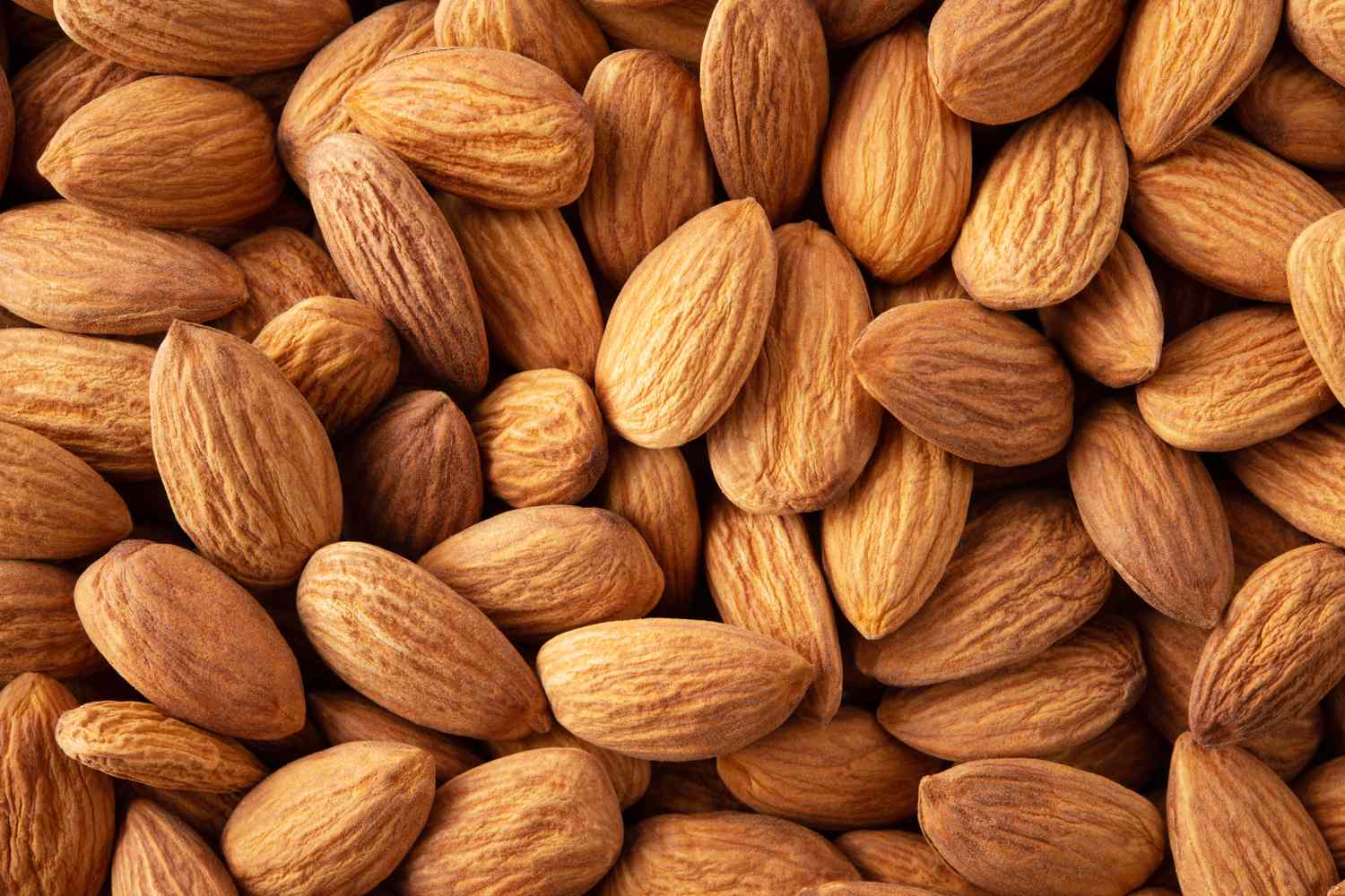 A closeup view of raw almonds in their husks scattered