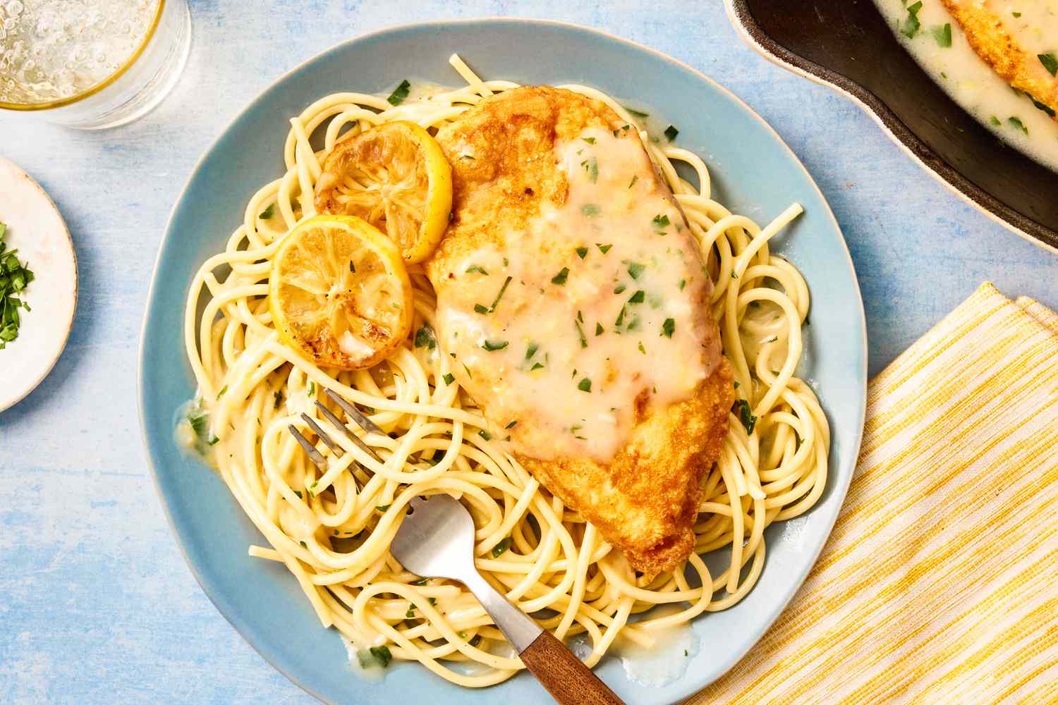 Chicken Francese on a bed of pasta on a plate with a fork