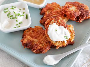 the best potato latkes on a blue platter with sour cream