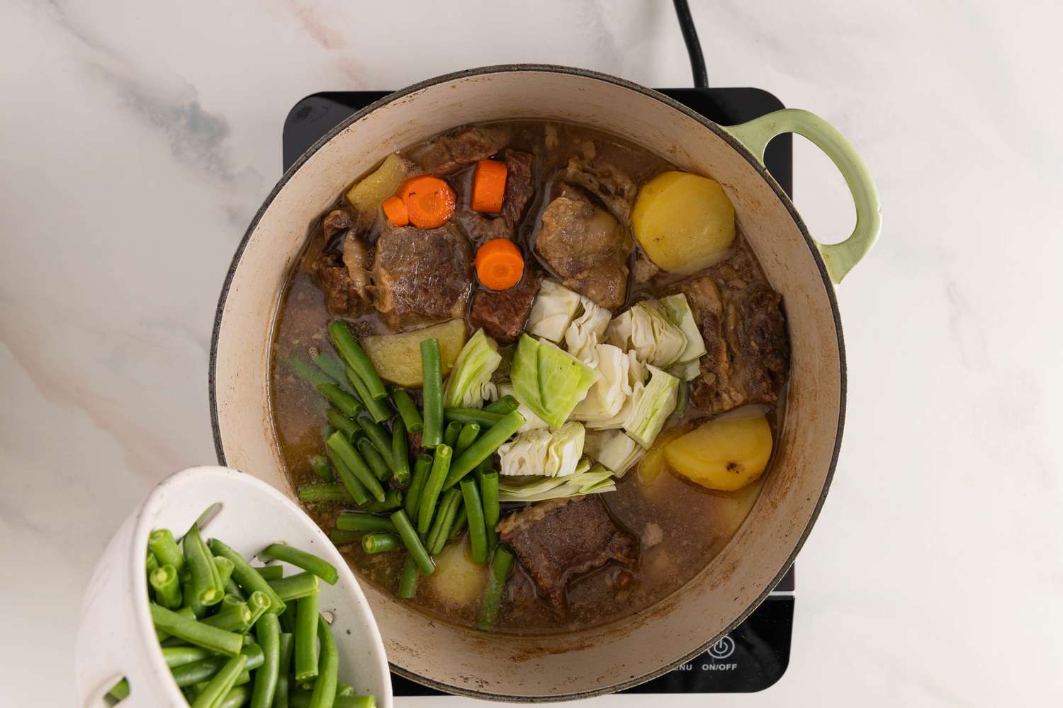 Vegetables added to Dutch oven for Filipino niligang baka recipe