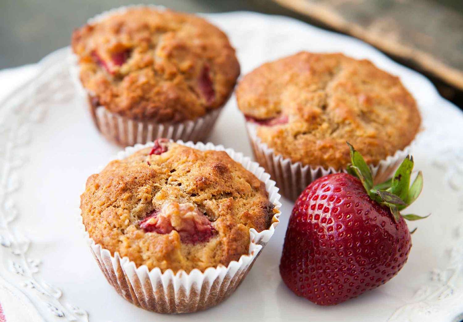 strawberry oatmeal muffins on a white plate with a fresh strawberry