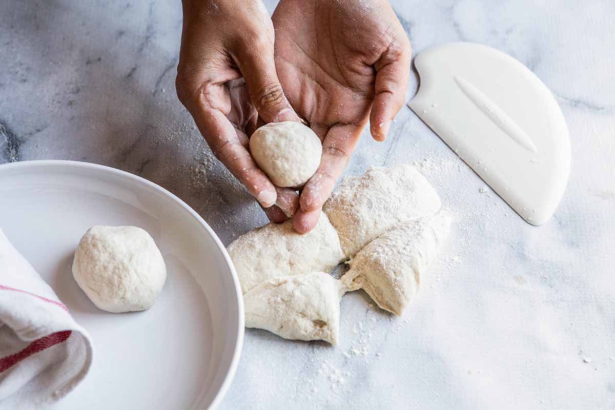 Easy Naan Recipe - person showing how to roll small segments of dough into balls.