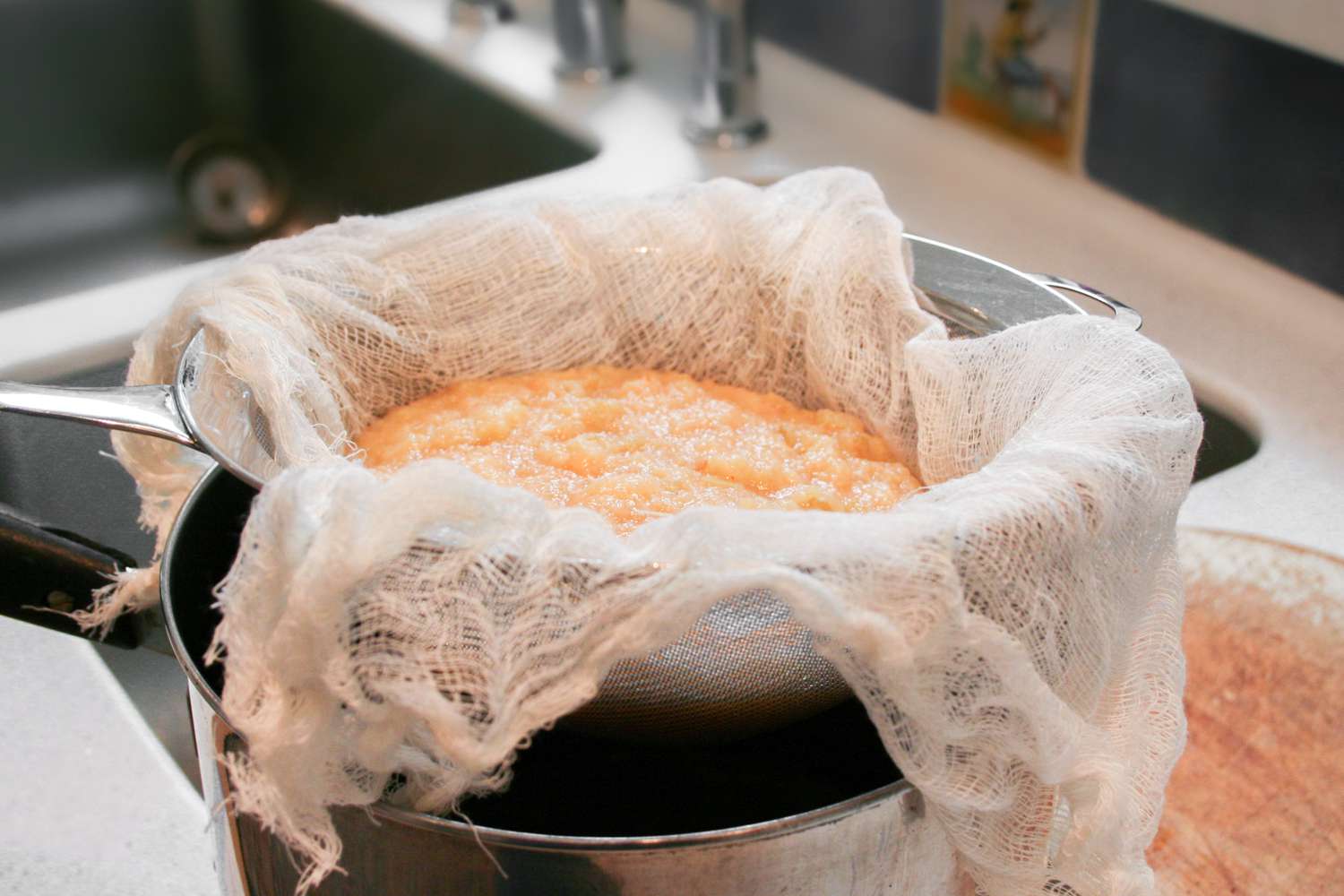 Straining cooked quince through a cheesecloth 