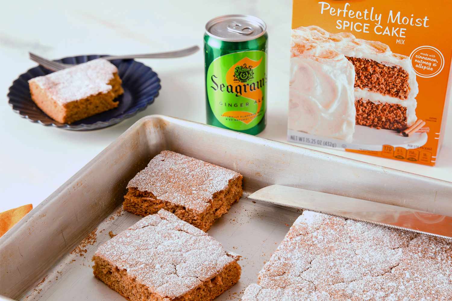 Sliced soda cake in a baking tray alongside a spice cake mix box and a can of soda