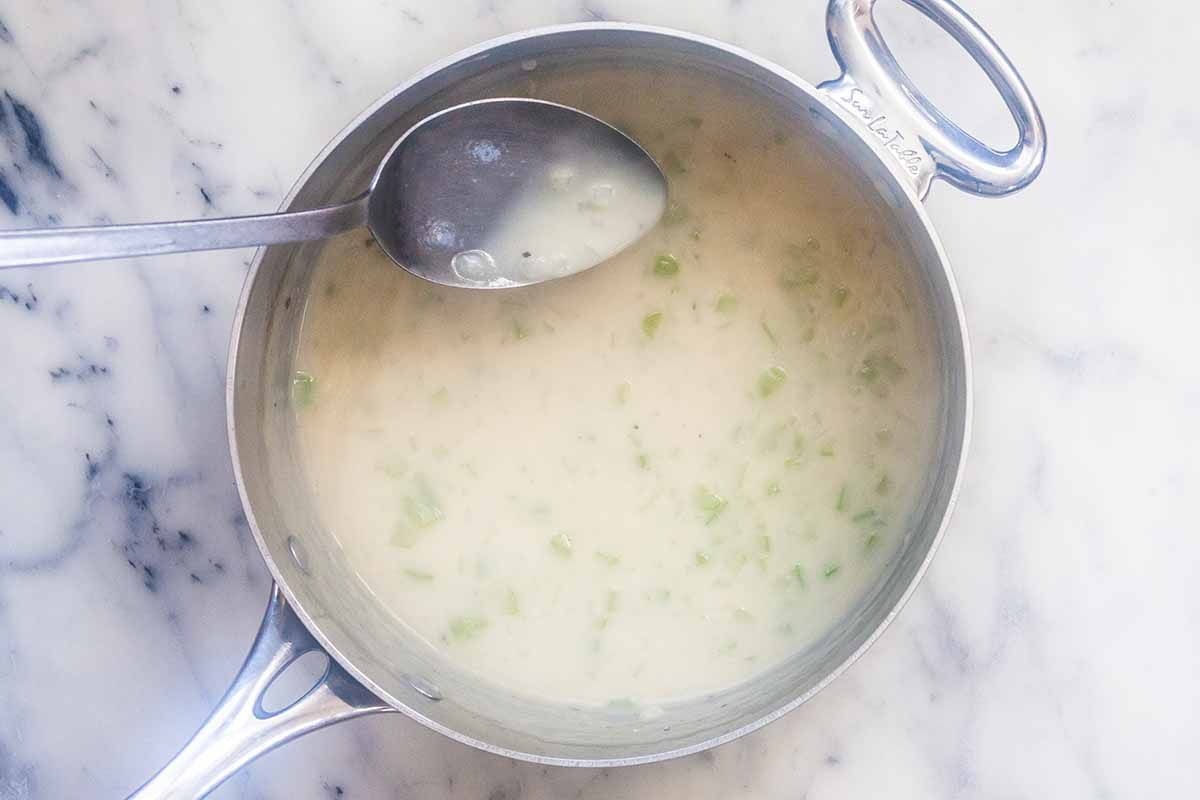 Thickened cream sauce in a sauce pot for homemade chicken noodle soup casserole.