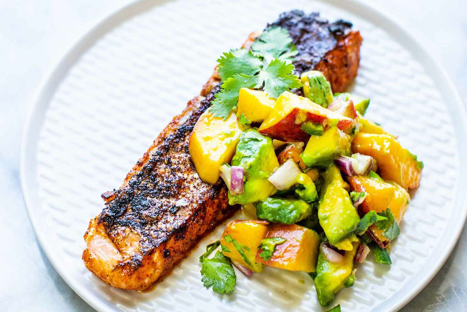 A plate with grilled salmon and peach salsa