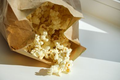 A paper bag with popcorn spilling out onto a surface