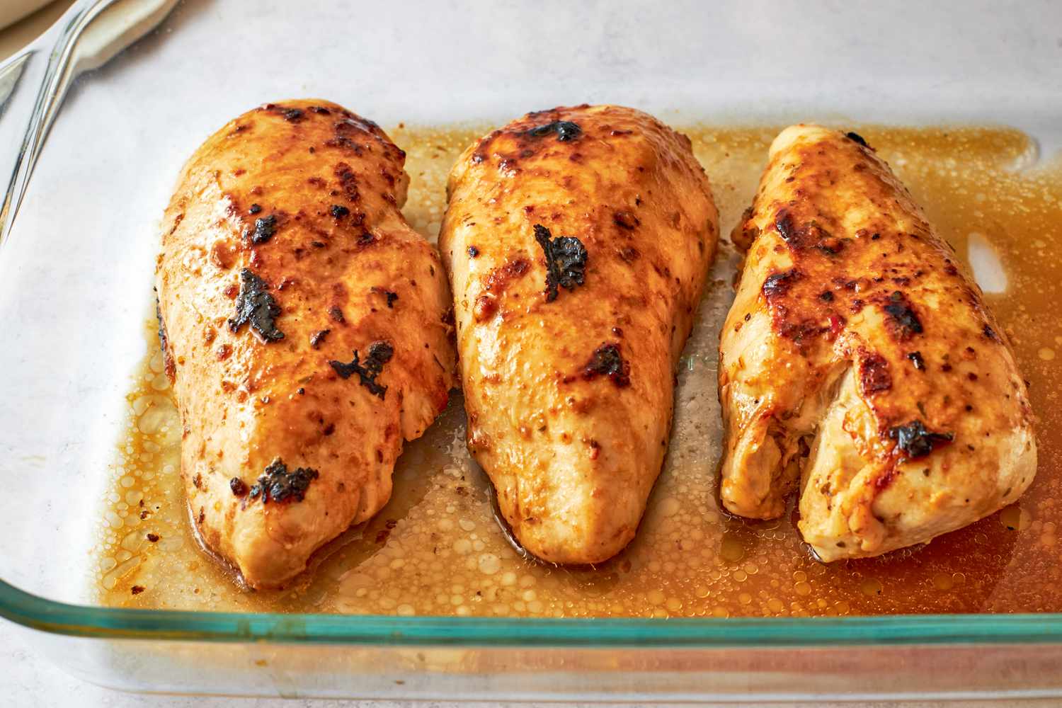 Side view of three marinated and cooked chicken breasts