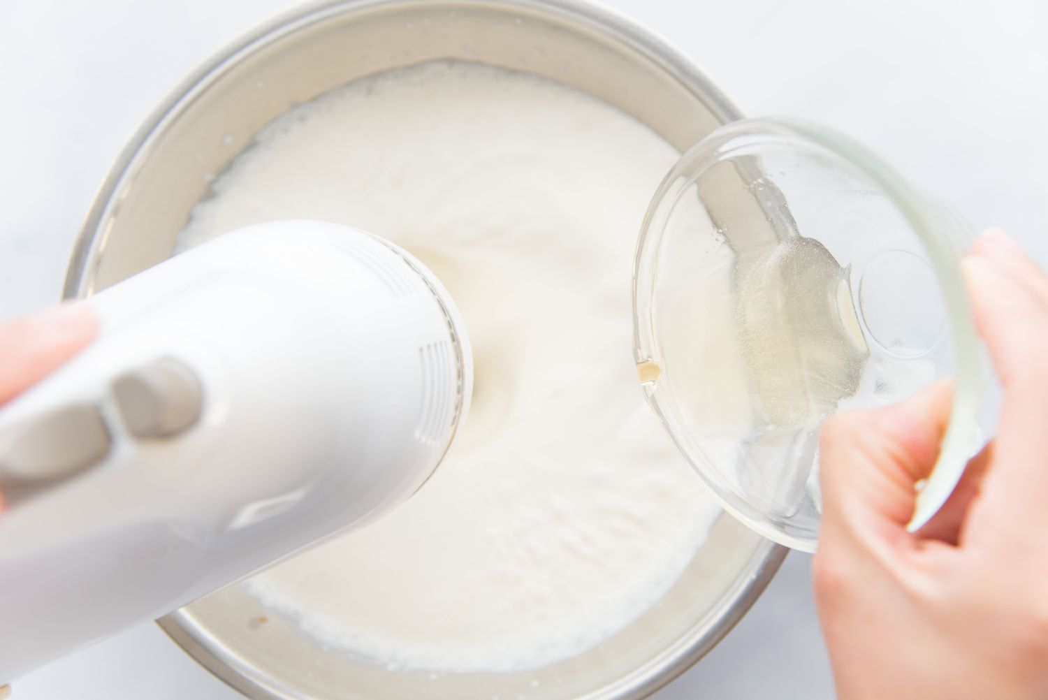 Adding gelatin to a bowl of whipped cream for a chocolate swiss roll.