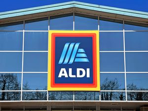 Exterior of an Aldi supermarket with a prominent sign displaying the store's logo near the entrance