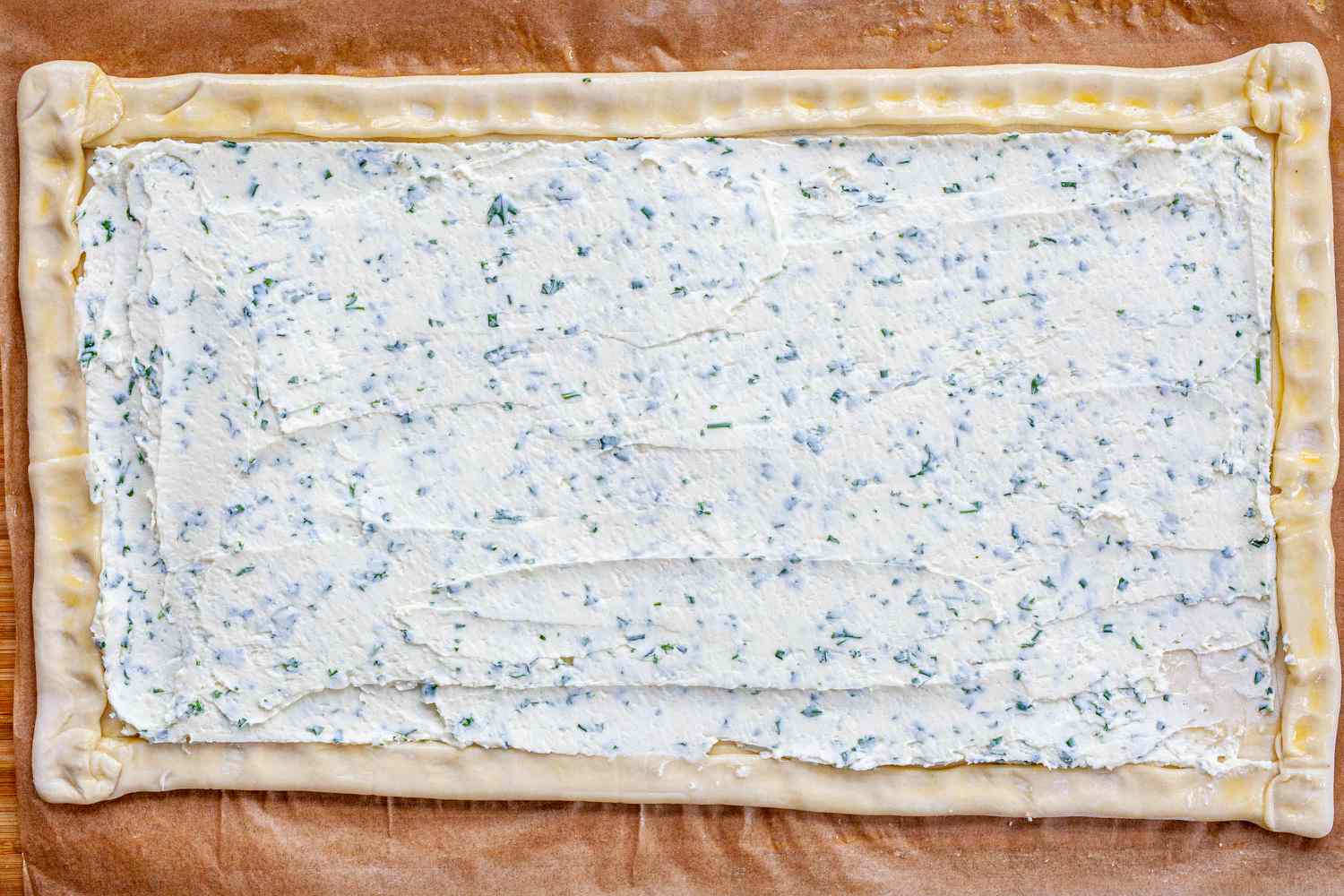 Goat cheese spread on puff pastry to make a Spring Asparagus Tart.