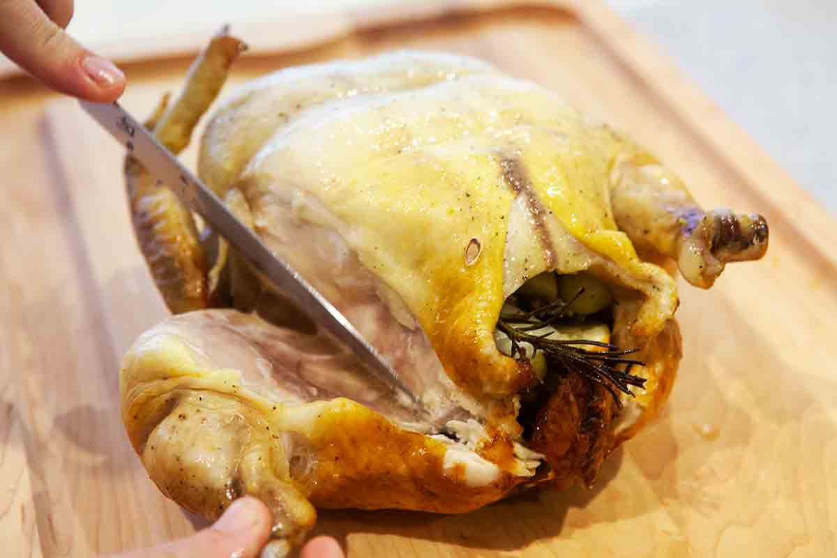 carve legs and thighs away from roast chicken with grapes