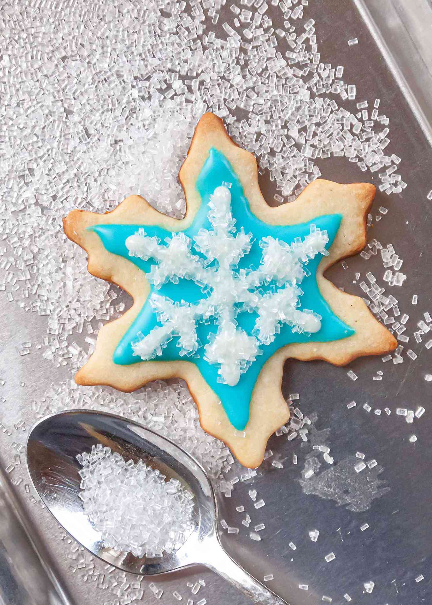 Sparkling sugar spooned over a snowflake cookie decorated with Easy Royal Icing Recipe.