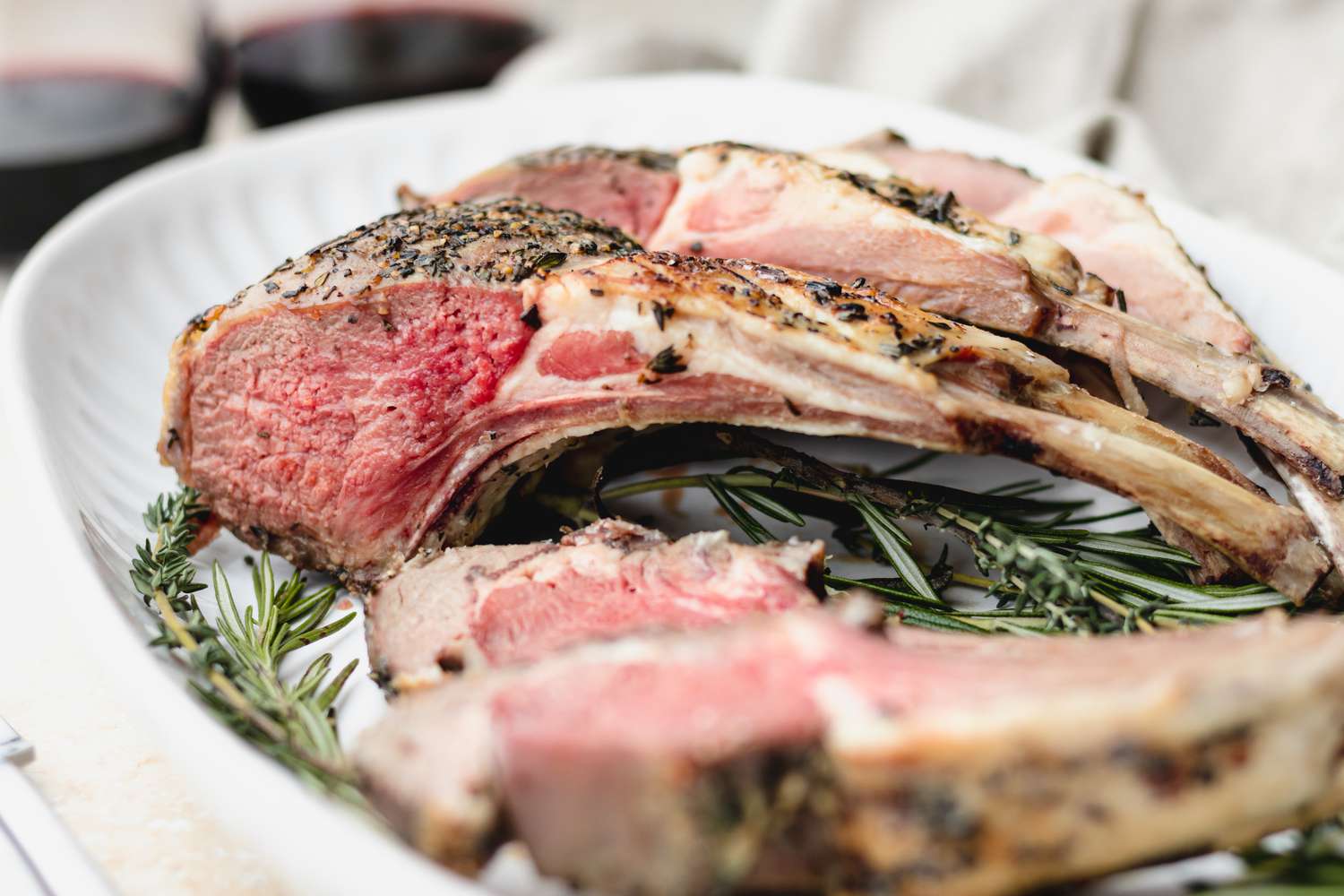 Rack of lamb cut into chops on platter with rosemary