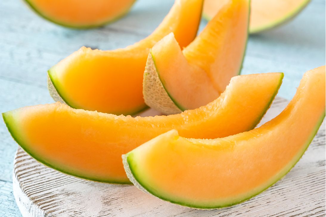 Sliced cantaloupe wedges arranged on a light-colored wooden surface