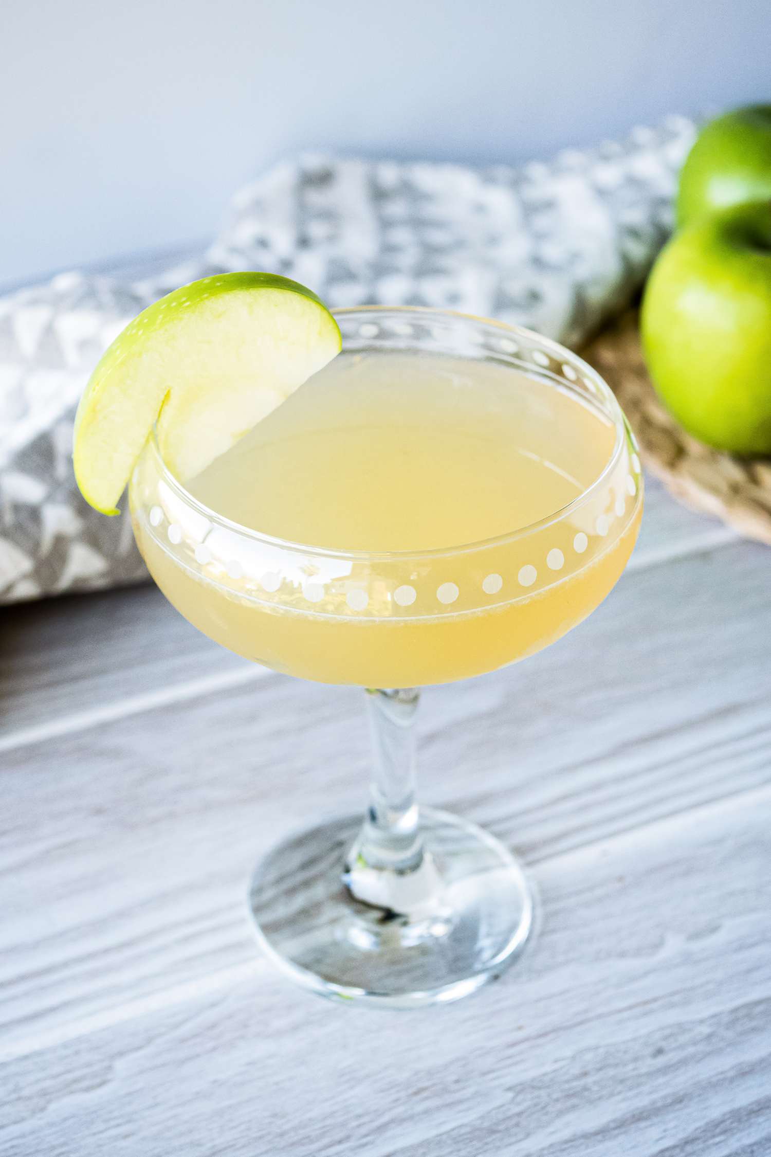Appletini cocktail garnished with a thin slice of green apple.