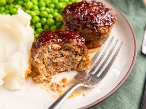 Meatloaf muffins served on a plate with peas and mashed potatoes