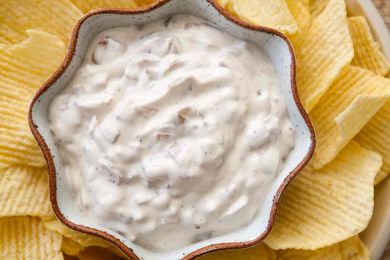 French Onion Dip in a scalloped bowl surrounded by potato chips