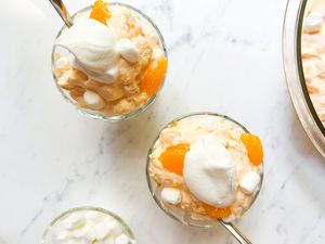 Orange creamsicle salad served in small glass bowls topped with whipped cream and marshmallows