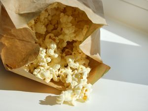 A paper bag with popcorn spilling out onto a surface