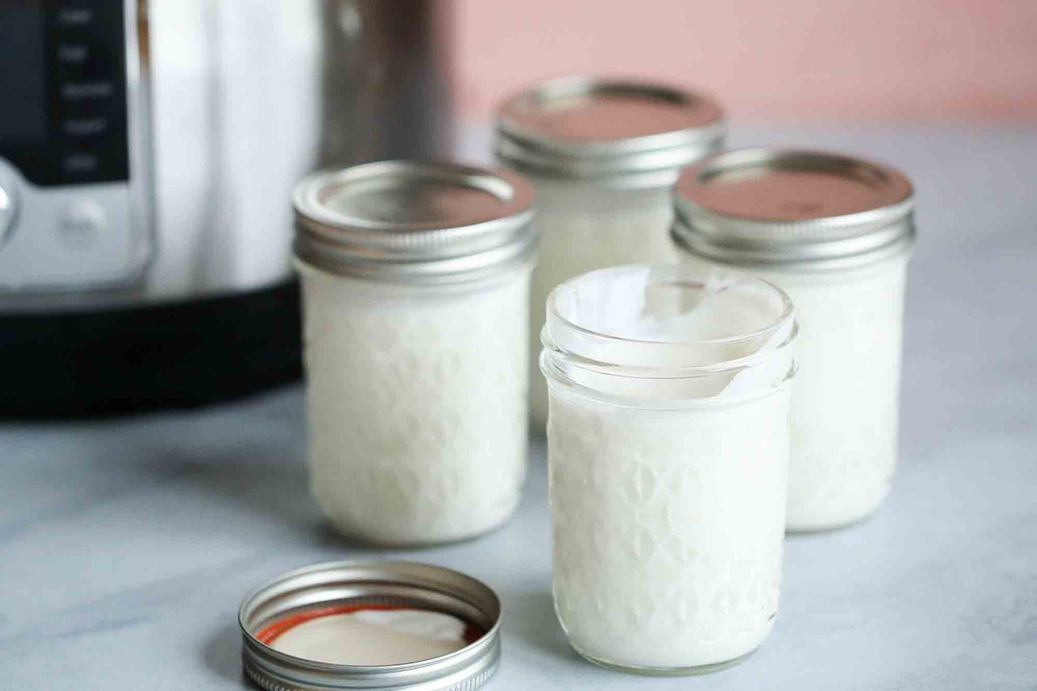 Jars of yogurt next to a pressure cooker