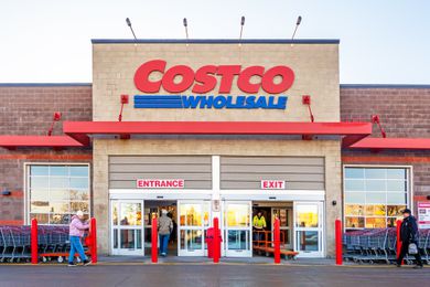 The front entrance of a Costco Wholesale store, with people walking in and out