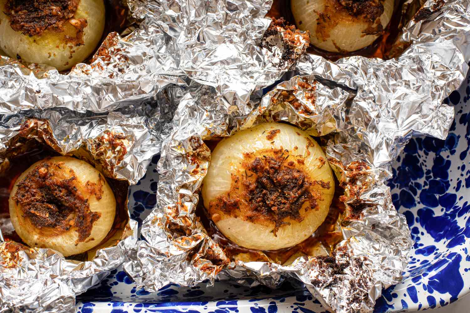 Baked onions in foil with seasonings on a tray