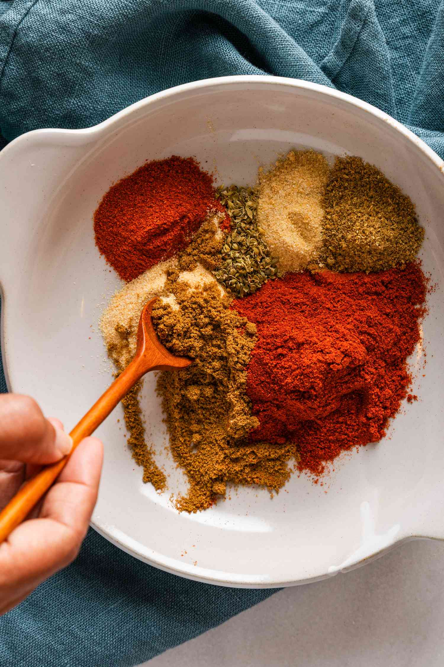 Spices being mixed together in a bowl to make homemade chili powder 