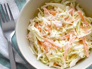 A bowl of coleslaw next to a fork