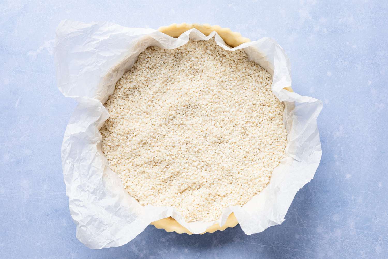 parchment paper and uncooked rice over the chilled tart crust in tart pan for cornflake tart recipe 