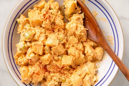overhead view of Deviled Egg Potato Salad in a bowl with a wooden spoon