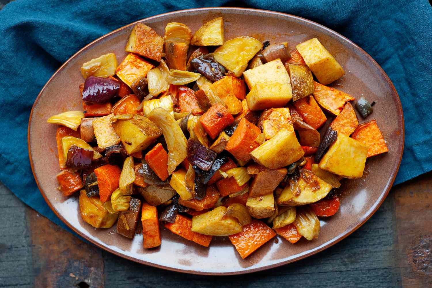 Overhead view of a easy roasted vegetables on a platter with a teal linen underneath.