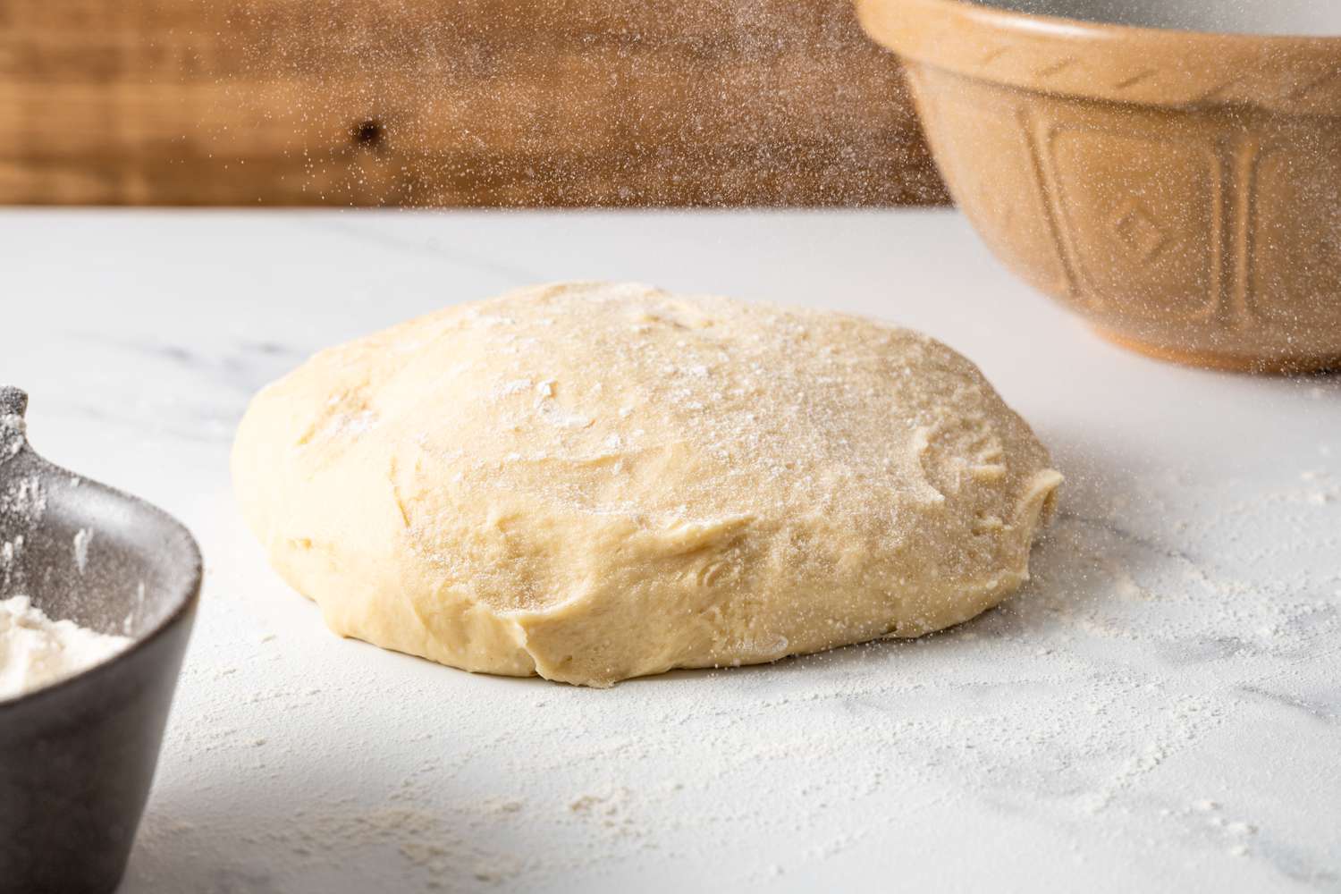 Flour over dough on kitchen counter