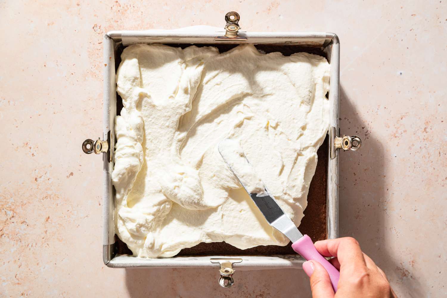 Overhead view of spreading the whipped topping onto the pudding layer for Chocolate Delight recipe