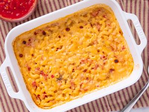 Baked macaroni and cheese in a rectangular dish served with a bowl of tomatobased sauce on the side